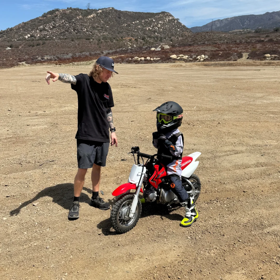 CMX coach explaining dirt bike controls to a student wearing riding gear